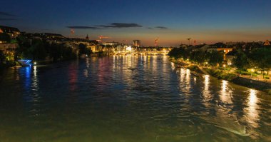 Arka planda köprü olan bir nehir. Su sakin ve gökyüzü karanlık. Huzurlu ve huzurlu bir sahne.