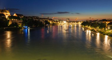 Arka planda köprü olan bir nehir. Su sakin ve gökyüzü karanlık. Huzurlu ve huzurlu bir sahne.