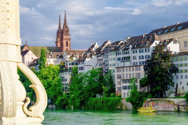 Geniş bir kilisesi ve şatosu olan Basel şehri. Gökyüzü mavi ve bazı bulutlar var.