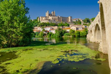 Saint-Nazir Katedrali. Arka planda şatosu olan bir kasabadan geçen bir nehir. Su sakin ve berrak. Çevredeki binaları yansıtıyor. Sükunet ve huzur kavramı