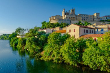 Saint-Nazir Katedrali. Arka planda şatosu olan bir kasabadan geçen bir nehir. Su sakin ve berrak. Çevredeki binaları yansıtıyor. Sükunet ve huzur kavramı