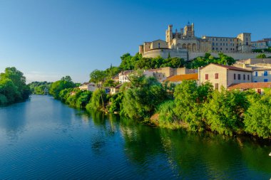 Saint-Nazir Katedrali. Arka planda şatosu olan bir kasabadan geçen bir nehir. Su sakin ve berrak. Çevredeki binaları yansıtıyor. Sükunet ve huzur kavramı
