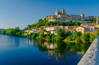 Saint-Nazir Katedrali. Arka planda şatosu olan bir kasabadan geçen bir nehir. Su sakin ve berrak. Çevredeki binaları yansıtıyor. Sükunet ve huzur kavramı
