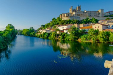 Saint-Nazir Katedrali. Arka planda şatosu olan bir kasabadan geçen bir nehir. Su sakin ve berrak. Çevredeki binaları yansıtıyor. Sükunet ve huzur kavramı