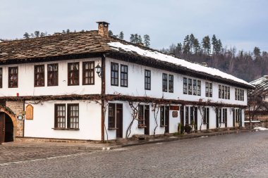 Tryavna. Taş çatılı ve tahta panjurlu bir ev. Panjurlar açık, içeri ışık giriyor. Ev eski ve kırsal bir havası var.