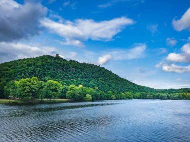 Yeşil yaz ormanı ve mavi göl manzarası.
