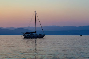 Akdeniz 'de limanda bir yat. Yunanistan 'da dağlarla gün batımı