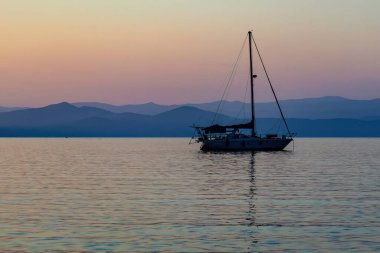 Akdeniz 'de limanda bir yat. Yunanistan 'da dağlarla gün batımı