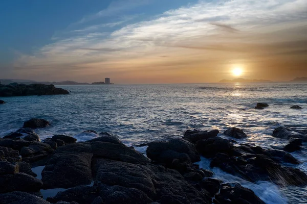 Sahilde büyük kayalıklarla gün batımı.