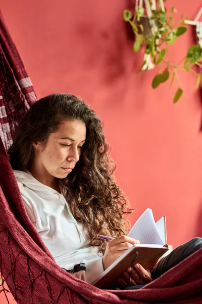 Woman writing in a hammock