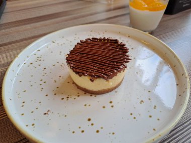 Round cheesecake with chocolate sauce topping served on the ceramic plate, ready to eat