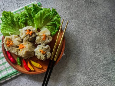 Chinese steamed dumpling or dim sum served in ceramic plate with chopsticks. Ready to eat with chili and sauce. Selective focus image