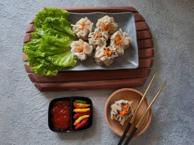 Chinese steamed dumpling or dim sum served in ceramic plate with chopsticks. Ready to eat with chili and sauce. Selective focus image