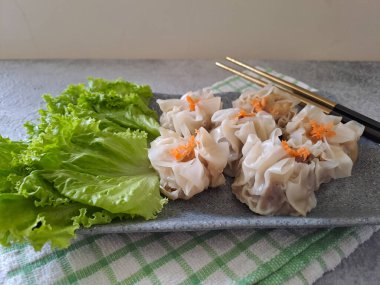 Chinese steamed dumpling or dim sum served in ceramic plate with chopsticks. Ready to eat with chili and sauce. Selective focus image