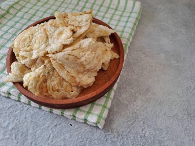 Emping melinjo, indonesian snacks or crackers. Made of belinjo (Gnetum gnemon) seeds with slightly bitter taste. Served in a wooden plate. selective focus image.