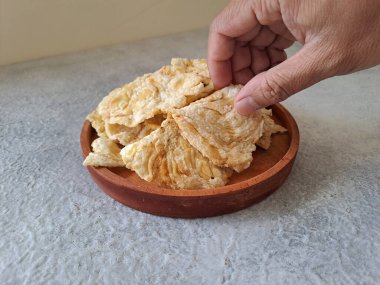 Emping melinjo, indonesian snacks or crackers. Made of belinjo (Gnetum gnemon) seeds with slightly bitter taste. Served in a wooden plate. selective focus image.