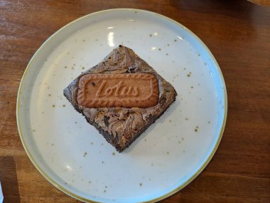 Malang - Indonesia, January 7, 2023 : Lotus brownie cake, chocolate brownie cake topped with lotus biscoff cookies served on the ceramic plate, ready to eat