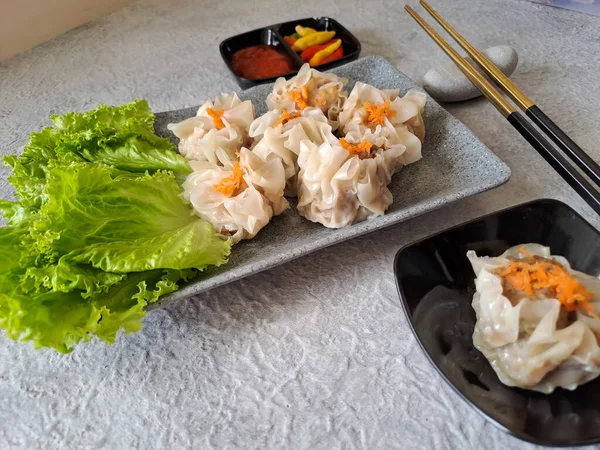 Chinese steamed dumpling or dim sum served in ceramic plate with chopsticks. Ready to eat with chili and sauce. Selective focus image