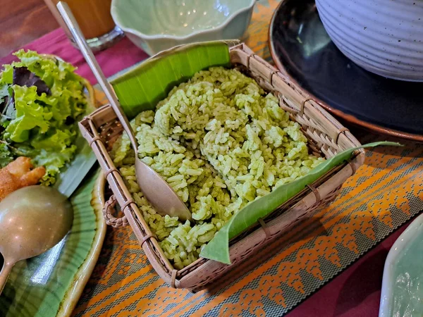 Mexican green rice, made of rice mixed with onion, cilantro and spinach. Served on the bamboo basket with banana leaf in the table