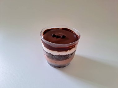 Layered dessert of chocolate trifle cake in a transparent cup isolated on white background. Sponge cake and chocolate mousse layers, sweet and delicious