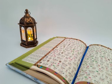 Open quran (arabic letters with indonesian translate), prayer beads and arabian lantern with arabic words 