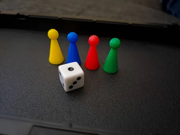 Colorful board game counters, chips or pieces and dice in a black box