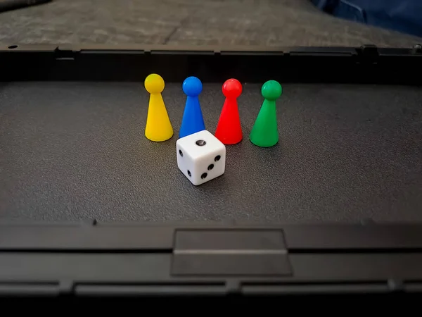 Colorful board game counters, chips or pieces and dice in a black box