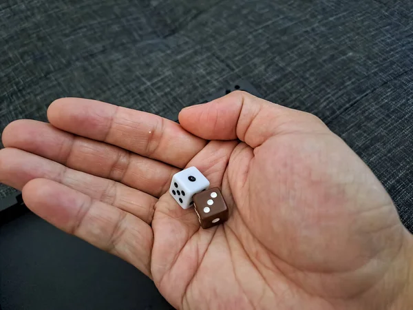 White and brown dices in human hand. The concept of luck, risk, gambling, or used for board game.