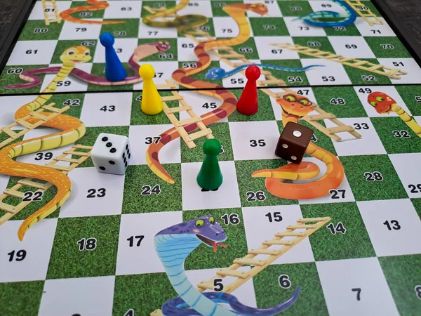 Close up view of snakes and ladders game board with dice and piece. Selective focus and blurred background