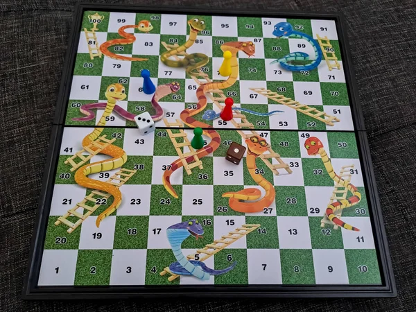 Close up view of snakes and ladders game board with dice and piece. Selective focus and blurred background