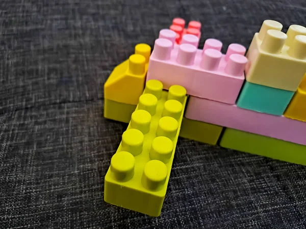 Pastel colored of plastic toy building blocks isolated on gray textured background. Selective focus