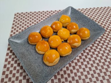 Ananas reçelli Endonezya tart kurabiyesi ya da Nastar olarak bilinen gri seramik tabağa yerleştirilmiş. Lebaran Idul Fitri ya da Kurban Bayramı 'nı kutlamak için popüler hizmet