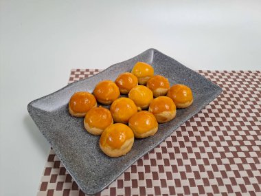 Ananas reçelli Endonezya tart kurabiyesi ya da Nastar olarak bilinen gri seramik tabağa yerleştirilmiş. Lebaran Idul Fitri ya da Kurban Bayramı 'nı kutlamak için popüler hizmet