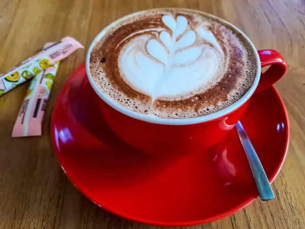 Kawa Latte Sztuką Serwowana Czerwonym Kubku Drewnianym Stole — Zdjęcie stockowe