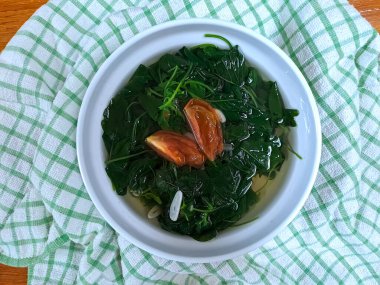 Sayur bükme bayam, ıspanak berrak sebze, Endonezya ıspanak çorbası. Ahşap arka planda beyaz kasede servis edilmiş. Ramazan 'da oruç tutmak için uygun