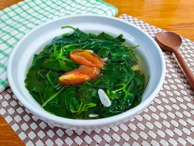 Sayur bükme bayam, ıspanak berrak sebze, Endonezya ıspanak çorbası. Ahşap arka planda beyaz kasede servis edilmiş. Ramazan 'da oruç tutmak için uygun