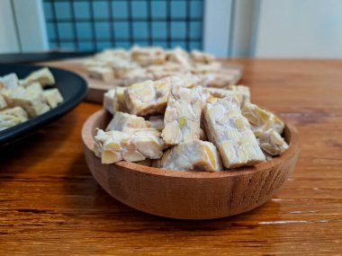Ahşap kaplamalı ahşap kapta kesilmiş çiğ Tempeh 'in yakın görüntüsü. Pişirmeye hazır.