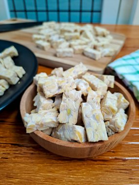 Ahşap kaplamalı ahşap kapta kesilmiş çiğ Tempeh 'in yakın görüntüsü. Pişirmeye hazır.