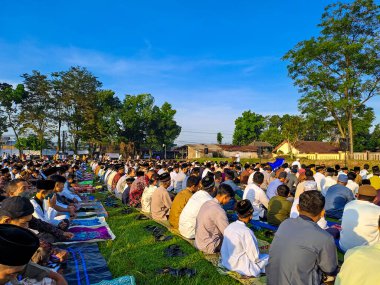 İnsanlar arka planda açık mavi gökyüzü ile bayram namazı kılmak için sahada toplanıyor. Yogyakarta, Endonezya, 21 Nisan 2023.