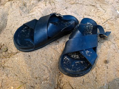 Kumsalda siyah sandaletler