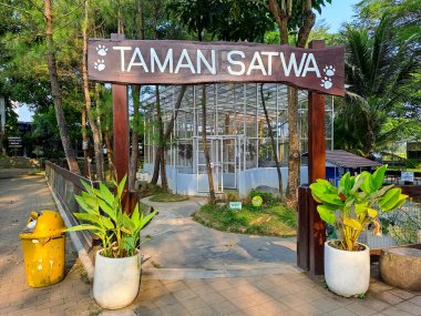 Aile tatili alternatifi olarak Endonezya şehir parkındaki hayvanat bahçesine giriş kapısı olan Taman Satwa (Fauna Park) yazılı ahşap bir kalas. Turist olmadan boş