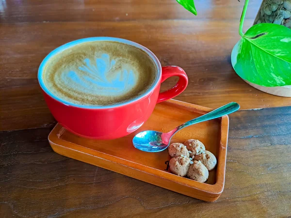 Kubek Gorącego Cappuccino Sztuką Latte Rano Podawany Czerwonym Kubku Ciasteczkiem — Zdjęcie stockowe
