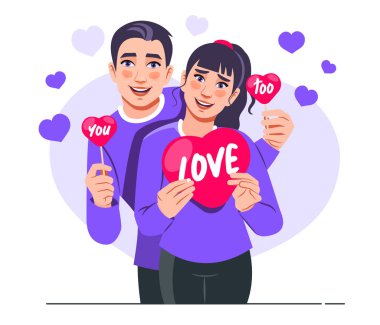 St. Valentine's Day Concept. Portrait of a cute young couple wearing purple t-shirts in love and holding red paper heart cards. Valentine's day celebration
