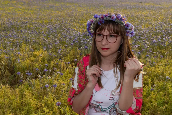 Açık arazide mavi çiçekli ve çiçekli bir kız.