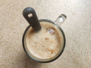 Kahverengi soyut arka planda kaşıkla kapuçino kahvesini bardakta kapat. Üst görüntü çekimi.