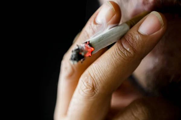 A person is smoking on a black background. Selective focus.