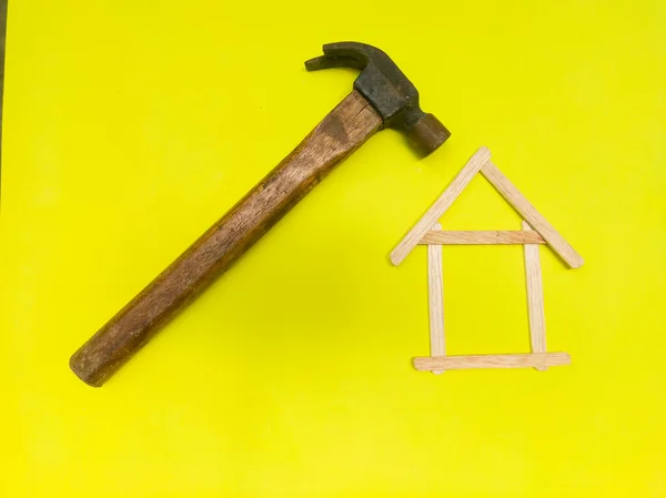 Illustration of a house renovation, house construction, under construction, or under repair. Close up shot of a hammer, and some ice cream sticks.
