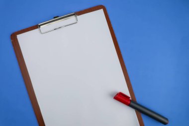 Ahşap bir not defterinde boş bir kağıt, mavi arka planda kırmızı bir işaret var..