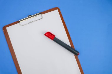 Ahşap bir not defterinde boş bir kağıt, mavi arka planda kırmızı bir işaret var..