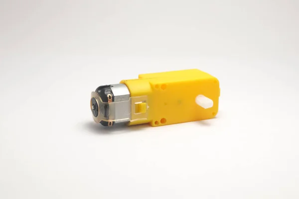 Beyaz arka planda sarı vites kutusuyla donatılmış güç soketi olan bir DC motoru. Elektronik hobiciler için DIY materyalleri.